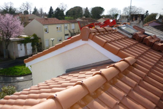 Pose des tuiles sur une toiture avec le faîtage